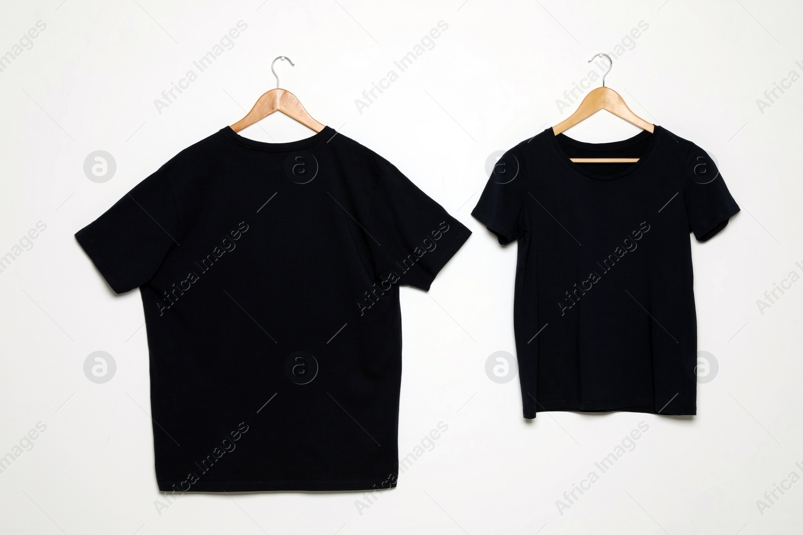 Photo of Hangers with blank t-shirts on white background. Mock up for design