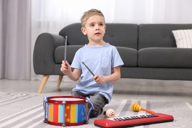 Little boy playing toy drum at home