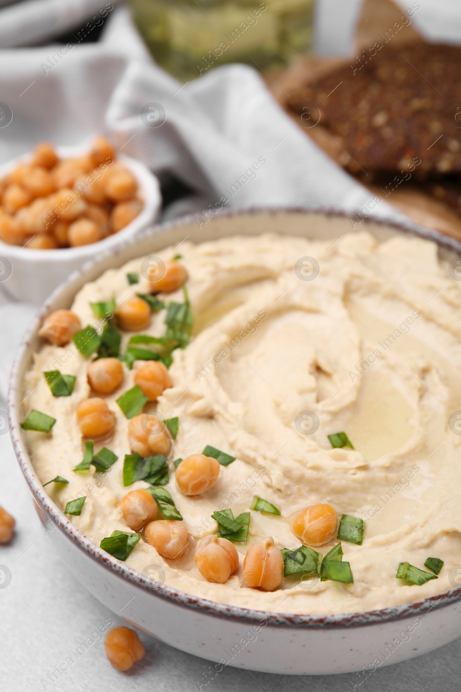 Photo of Delicious hummus with chickpeas served on light grey table, closeup