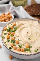 Delicious hummus with chickpeas served on light grey table, closeup