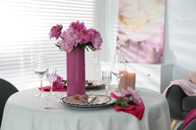 Beautiful table setting with pink peonies and burning candles