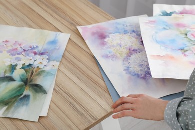 Woman holding painting of flowers indoors, closeup. Watercolor artwork