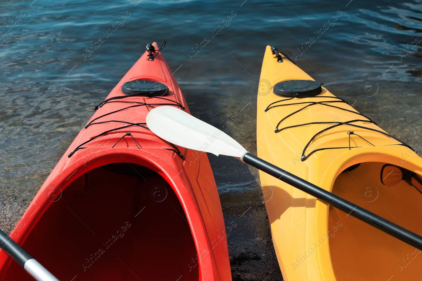 Photo of Modern kayaks with paddle on river, closeup. Summer camp activity