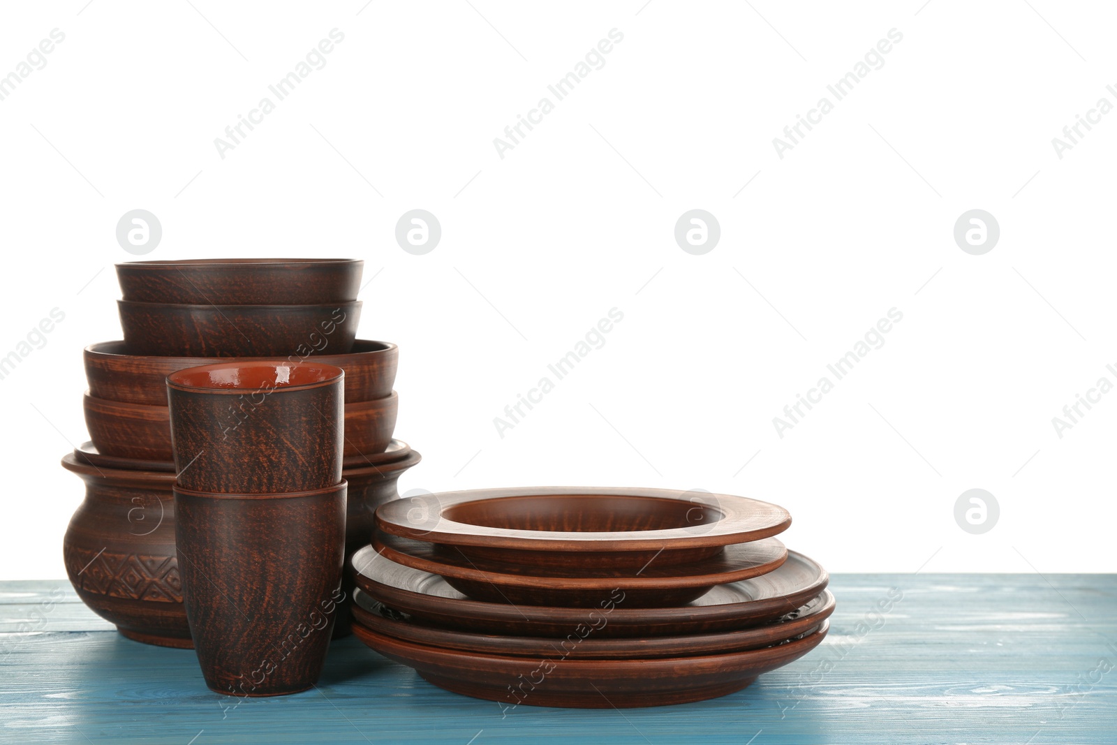 Photo of Different clay dishware on light blue wooden table against white background