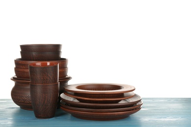 Different clay dishware on light blue wooden table against white background