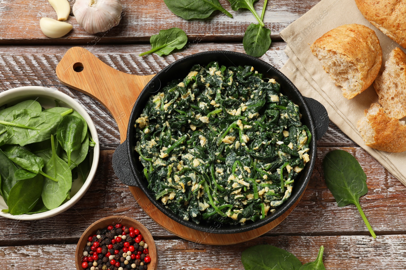 Photo of Tasty spinach dip with eggs in dish served on wooden table, flat lay