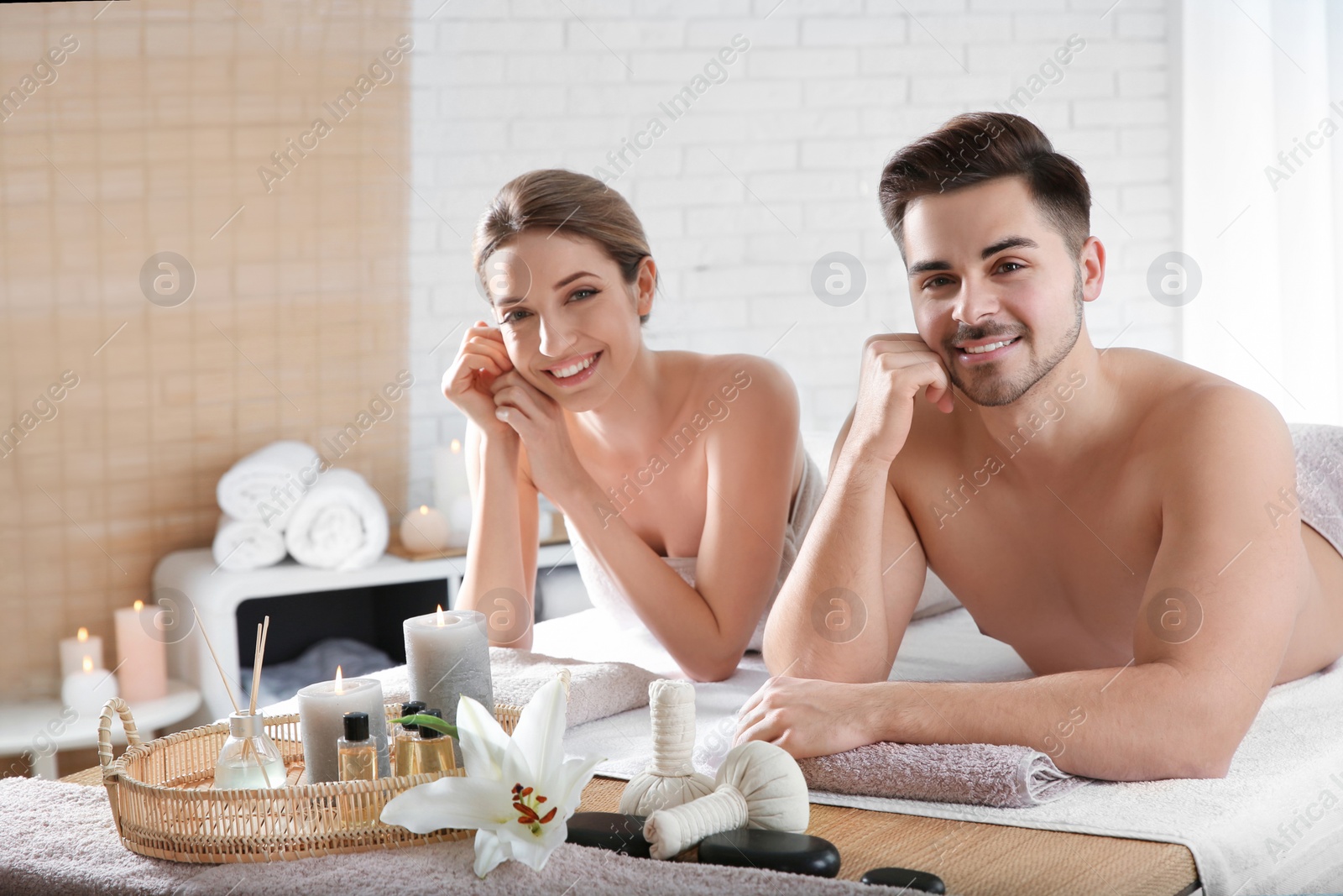 Photo of Young couple with spa essentials in wellness center