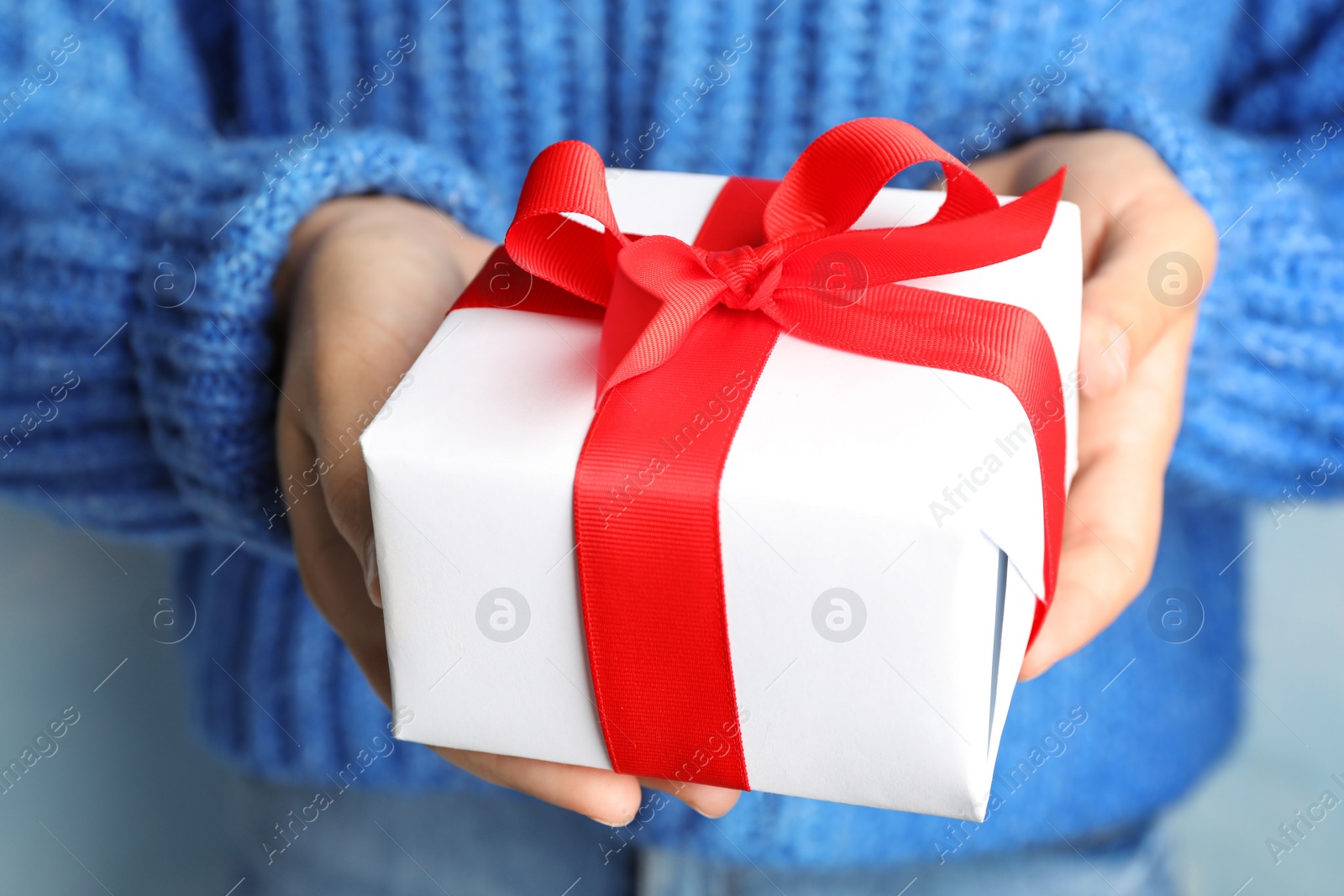 Photo of Young woman holding Christmas gift, closeup view