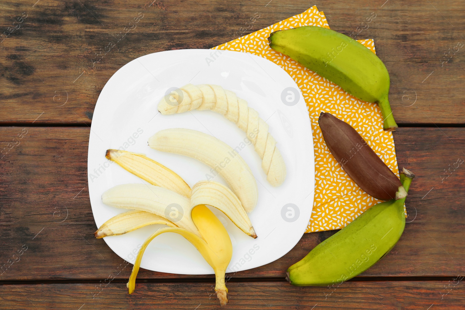 Photo of Whole and cut bananas on wooden table, flat lay