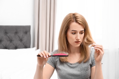 Attractive young woman brushing hair in bedroom