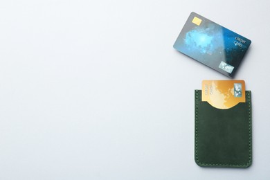 Woman holding leather card holder with credit cards on light grey background, top view. Space for text