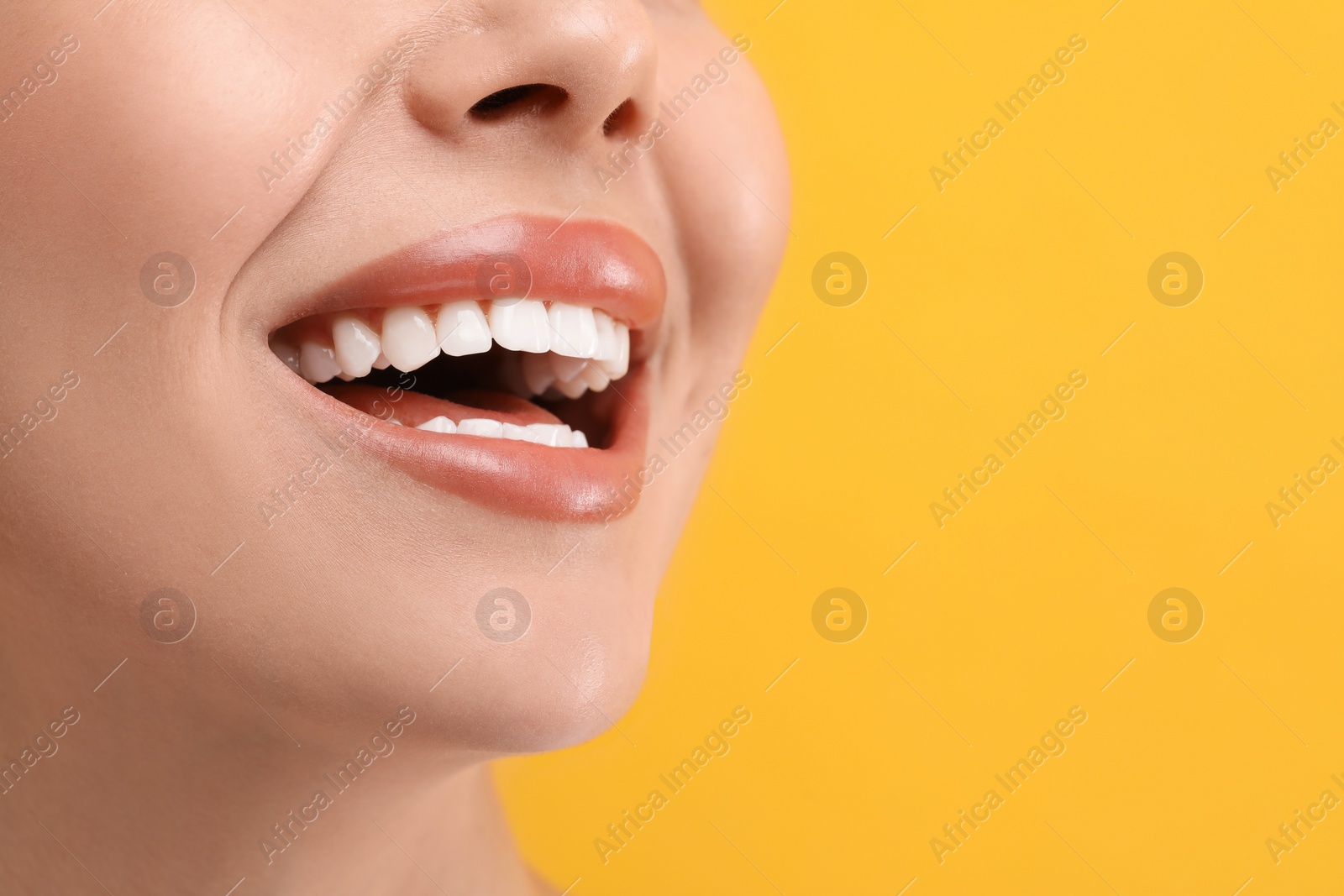 Photo of Woman with clean teeth smiling on yellow background, closeup. Space for text