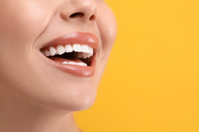 Photo of Woman with clean teeth smiling on yellow background, closeup. Space for text