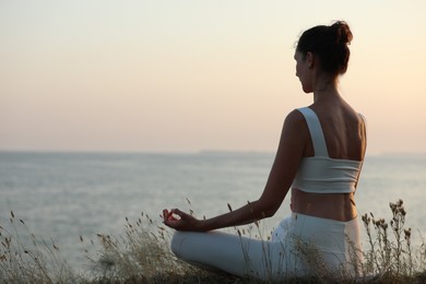 Photo of Woman meditating near sea. Space for text