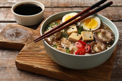 Noodle soup. Bowl of delicious ramen and chopsticks on wooden table, closeup