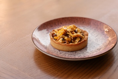 Plate with delicious cake on wooden table