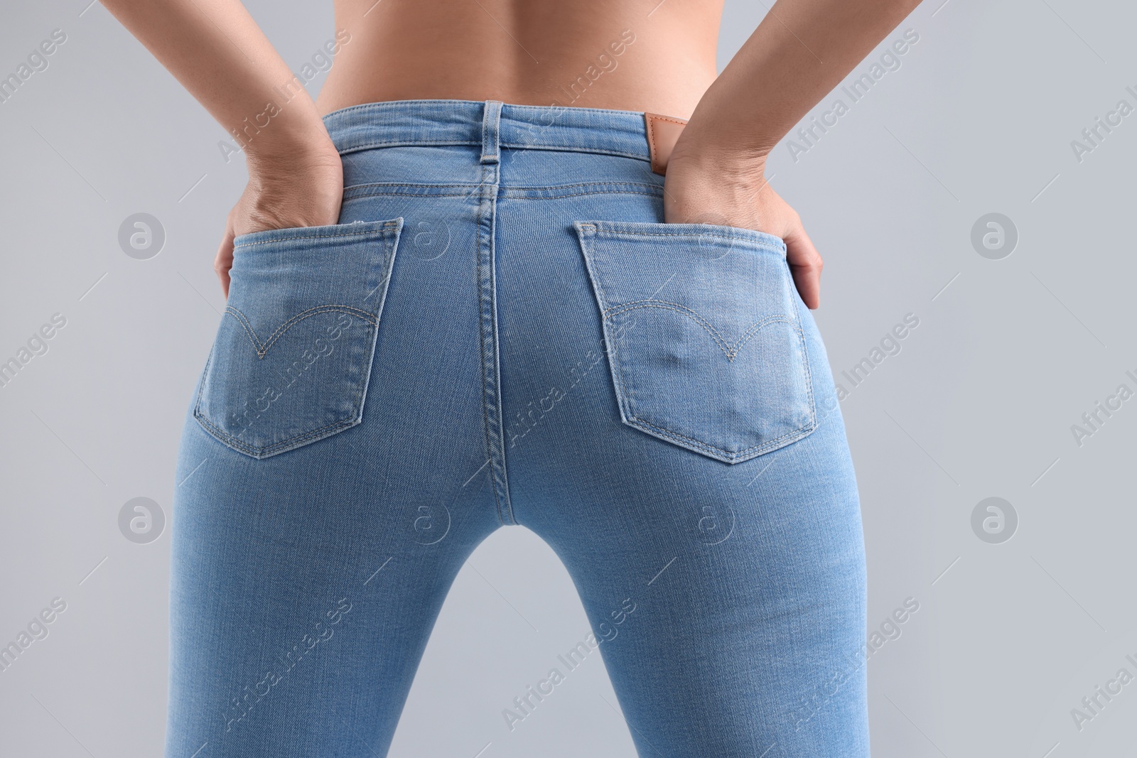 Photo of Woman wearing stylish jeans on light gray background, closeup