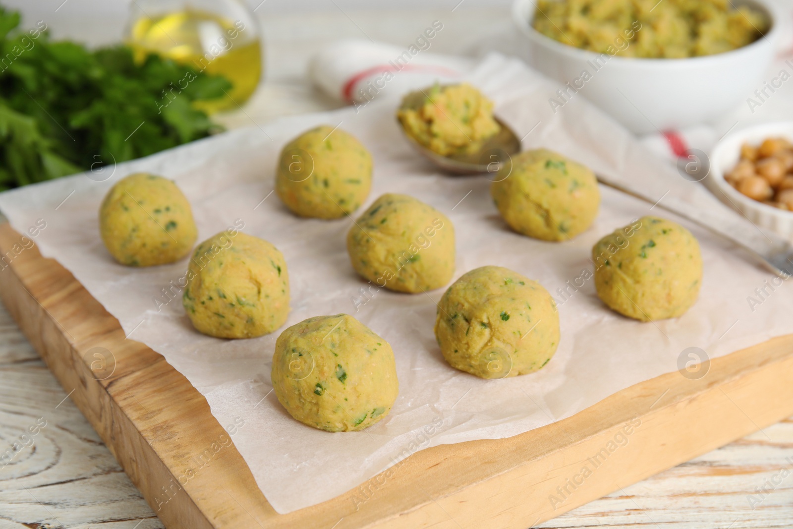 Photo of Many raw falafel balls on white wooden table