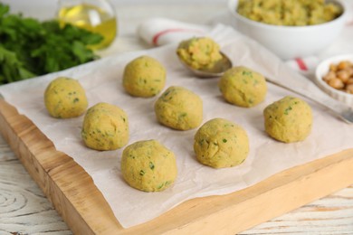 Many raw falafel balls on white wooden table