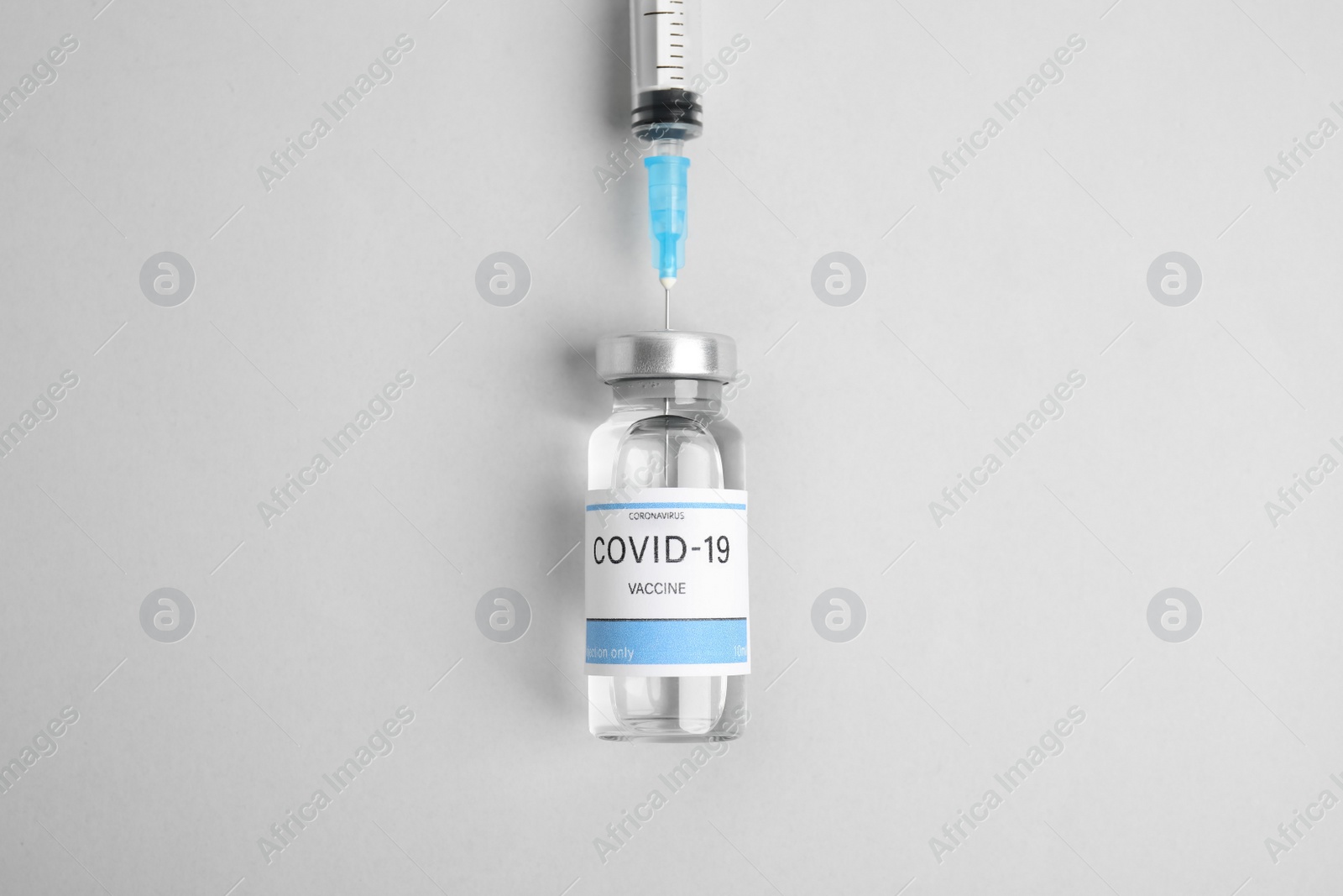 Photo of Filling syringe with coronavirus vaccine on light background, flat lay