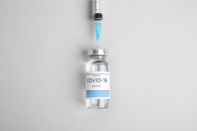 Photo of Filling syringe with coronavirus vaccine on light background, flat lay