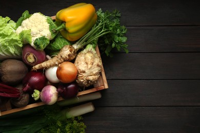 Photo of Crate full of different vegetables on black wooden table, top view with space for text. Farmer harvesting