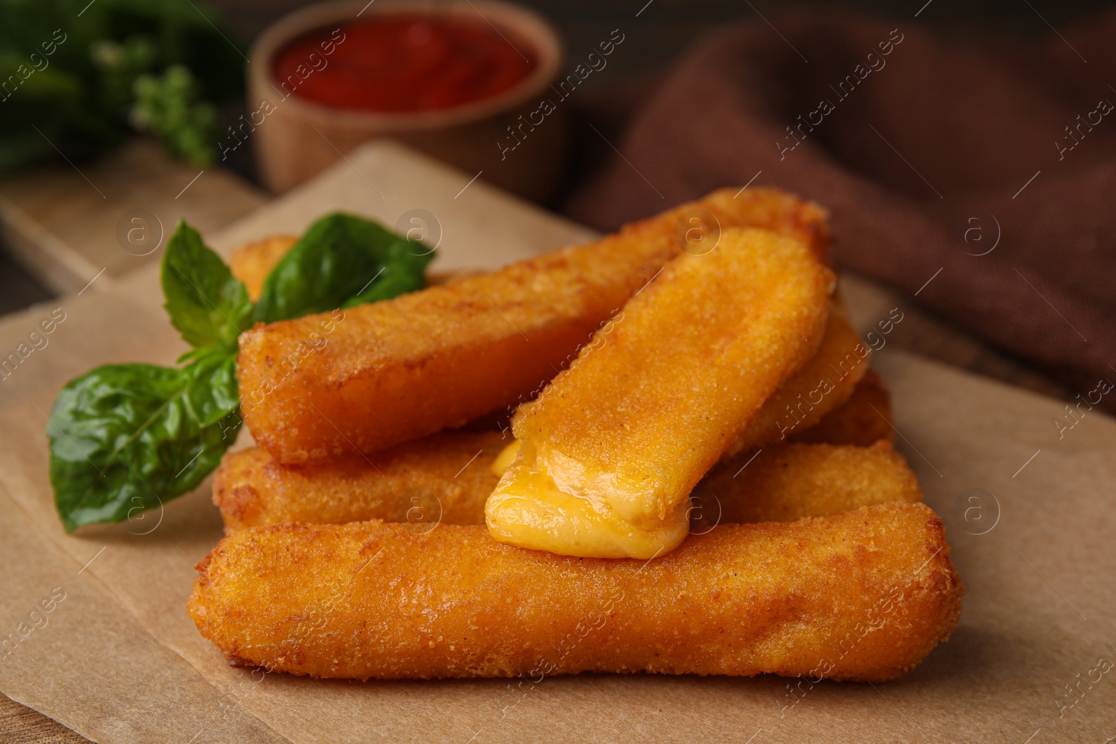 Photo of Tasty fried mozzarella sticks and basil on table, closeup