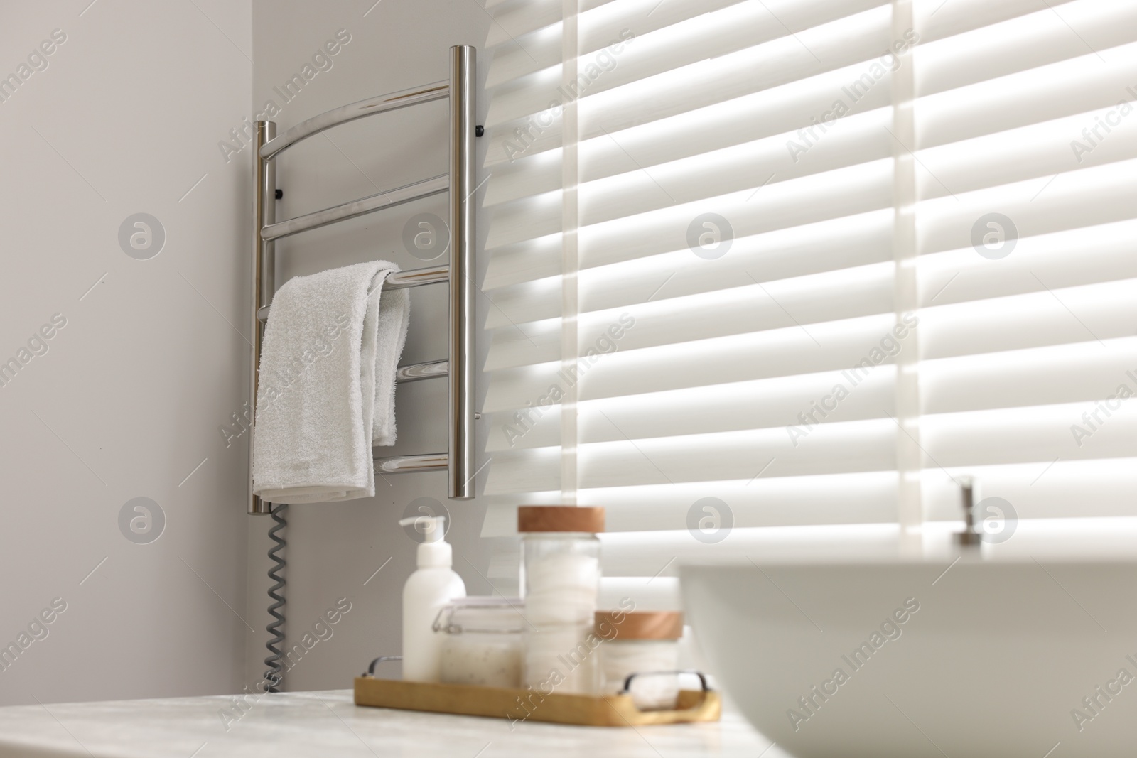 Photo of Heated rail with towel on white wall in bathroom, space for text