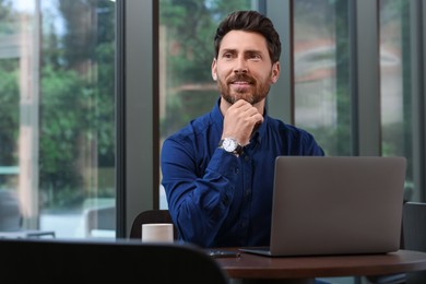 Photo of Man with laptop at table in cafe