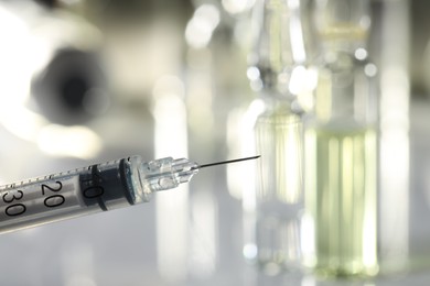 Photo of Syringe with medicine against blurred background, closeup. Space for text