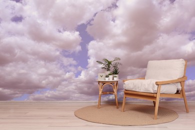 Image of Beautiful sky with clouds as wallpaper pattern in room. Side table with houseplants and armchair near wall