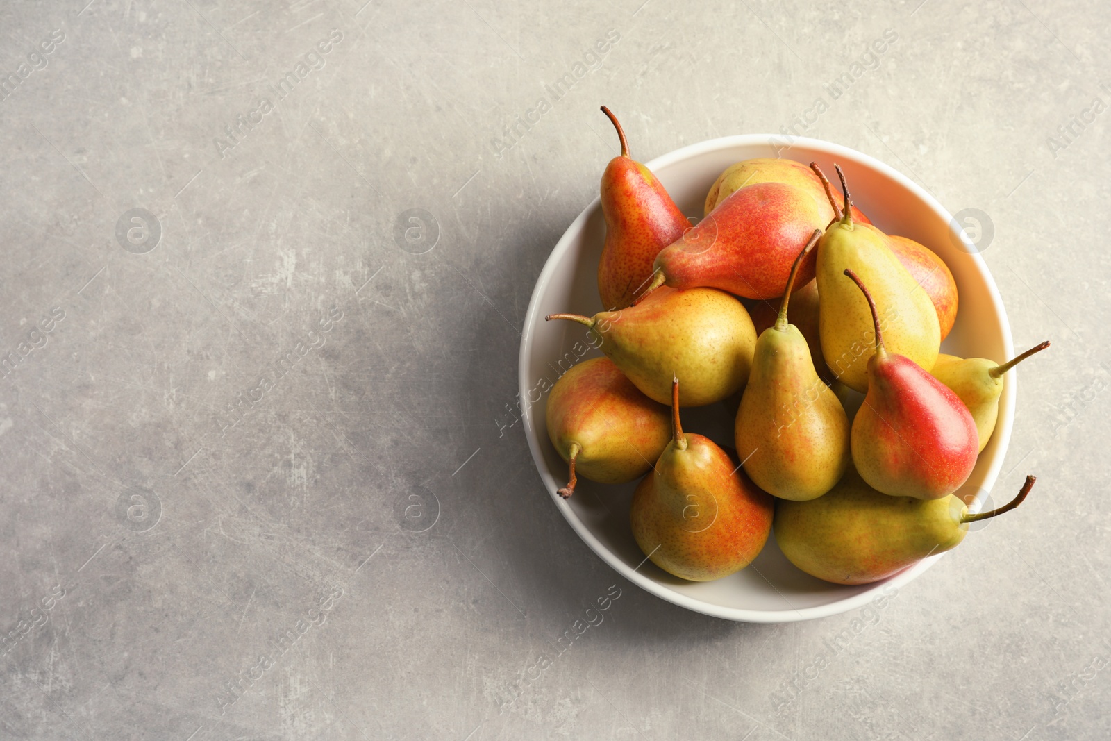 Photo of Plate with ripe pears on grey background, top view. Space for text