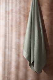 Photo of Soft towel hanging on textured wall indoors, space for text