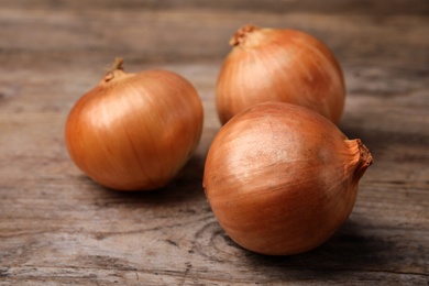 Photo of Ripe onions on rustic wooden table, closeup