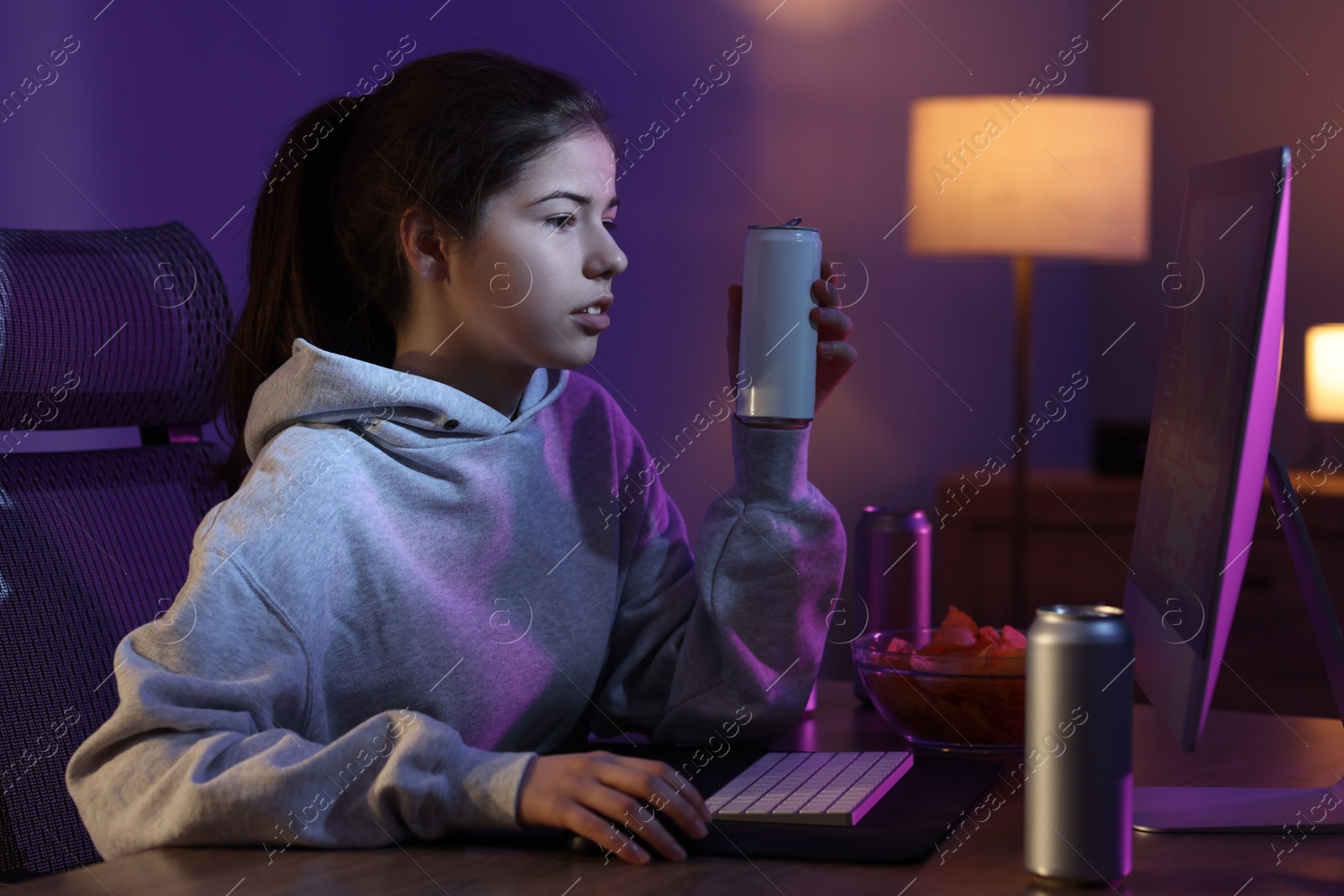 Photo of Girl with energy drink playing computer game at home