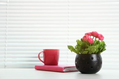 Photo of Window with blinds, beautiful potted plant, notebook and cup on sill, space for text