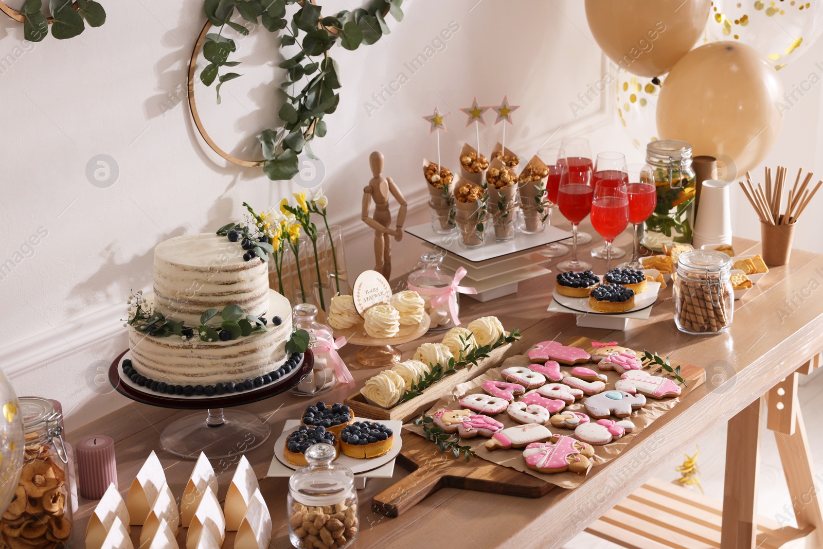 Photo of Baby shower party. Different delicious treats on wooden table indoors