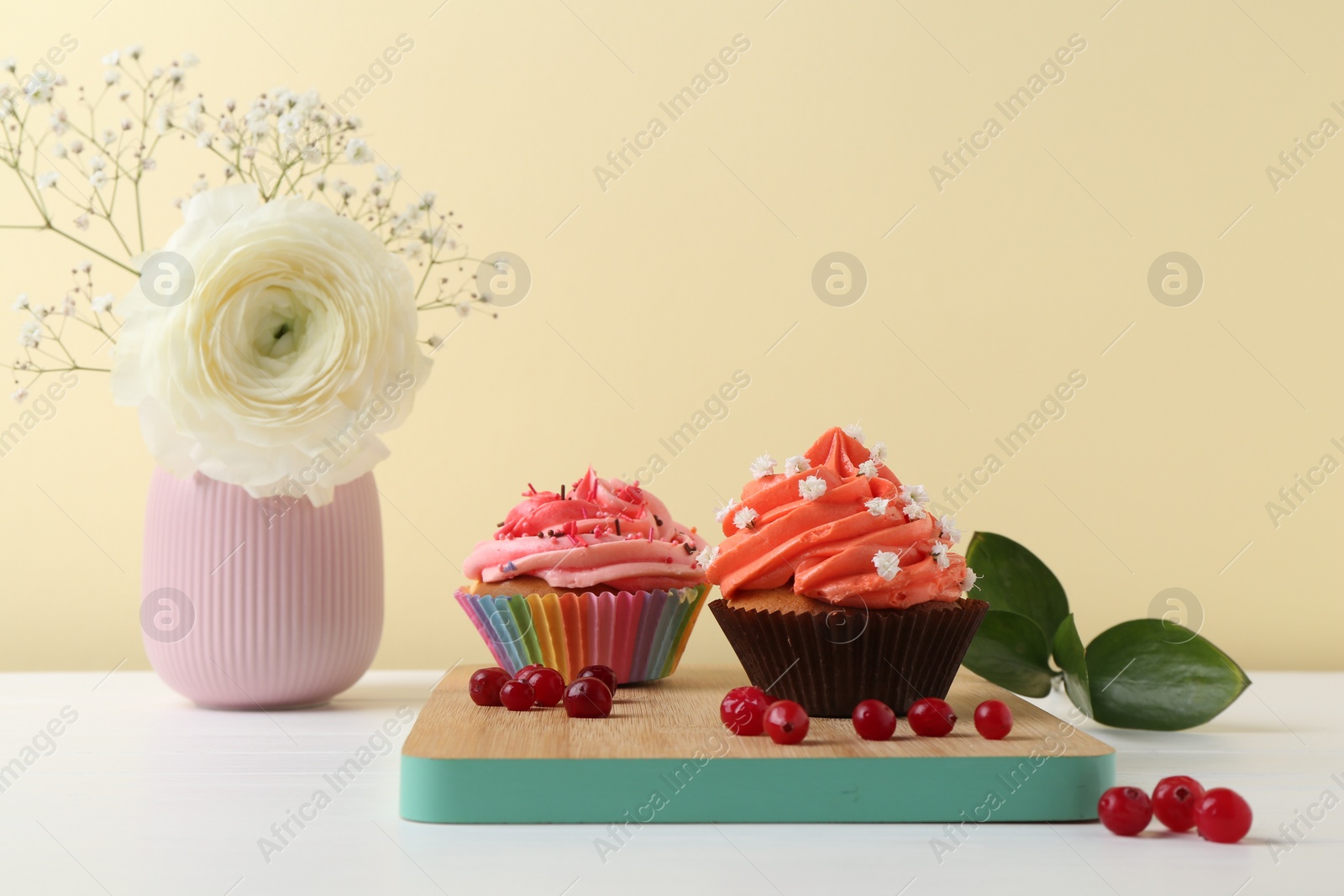 Photo of Delicious cupcake with bright cream and flowers on white wooden table