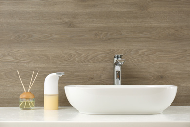 Photo of Modern automatic soap dispenser near sink in bathroom