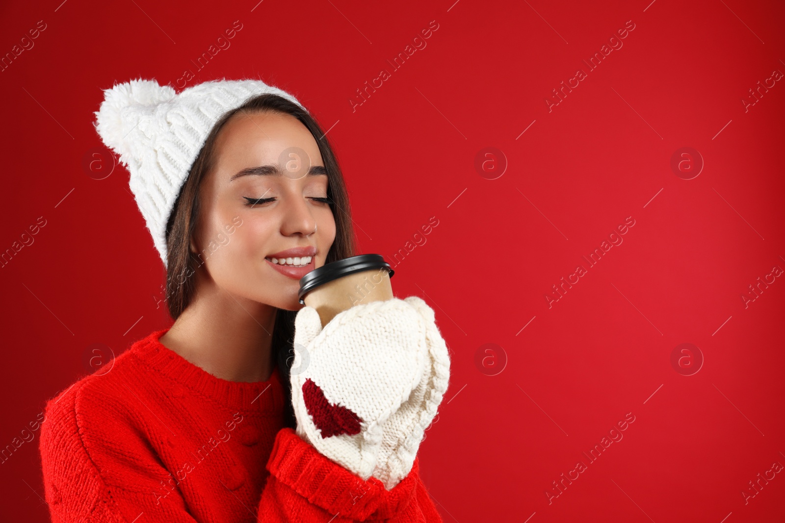 Photo of Happy beautiful woman with paper cup of mulled wine on red background. Space for text