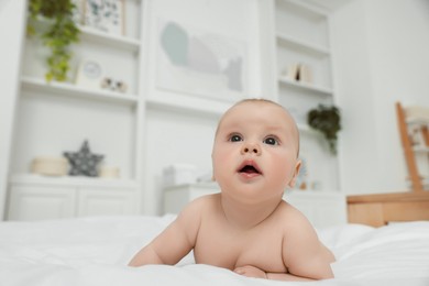 Photo of Cute baby lying on white bed at home, space for text
