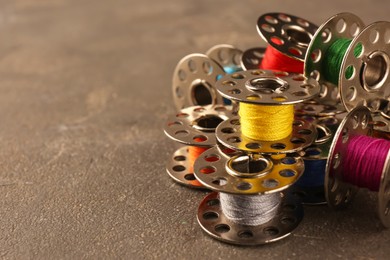 Photo of Set of color sewing threads on grey table, closeup. Space for text