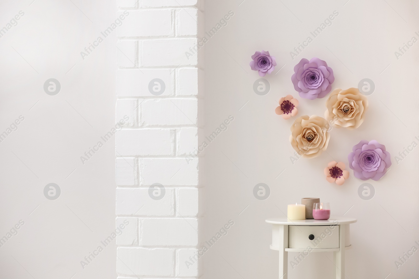 Photo of Stylish room interior with floral decor, table and candles, space for text