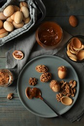 Photo of Freshly baked homemade walnut shaped cookies with nuts and boiled condensed milk on wooden table, flat lay