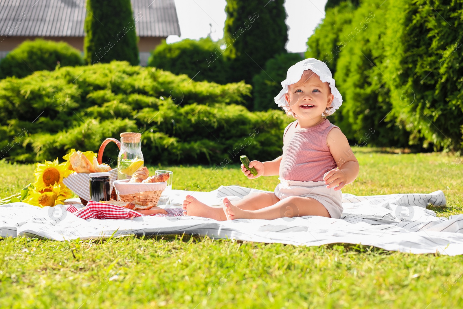 Photo of Cute child sitting on picnic blanket in garden