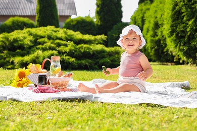 Cute child sitting on picnic blanket in garden