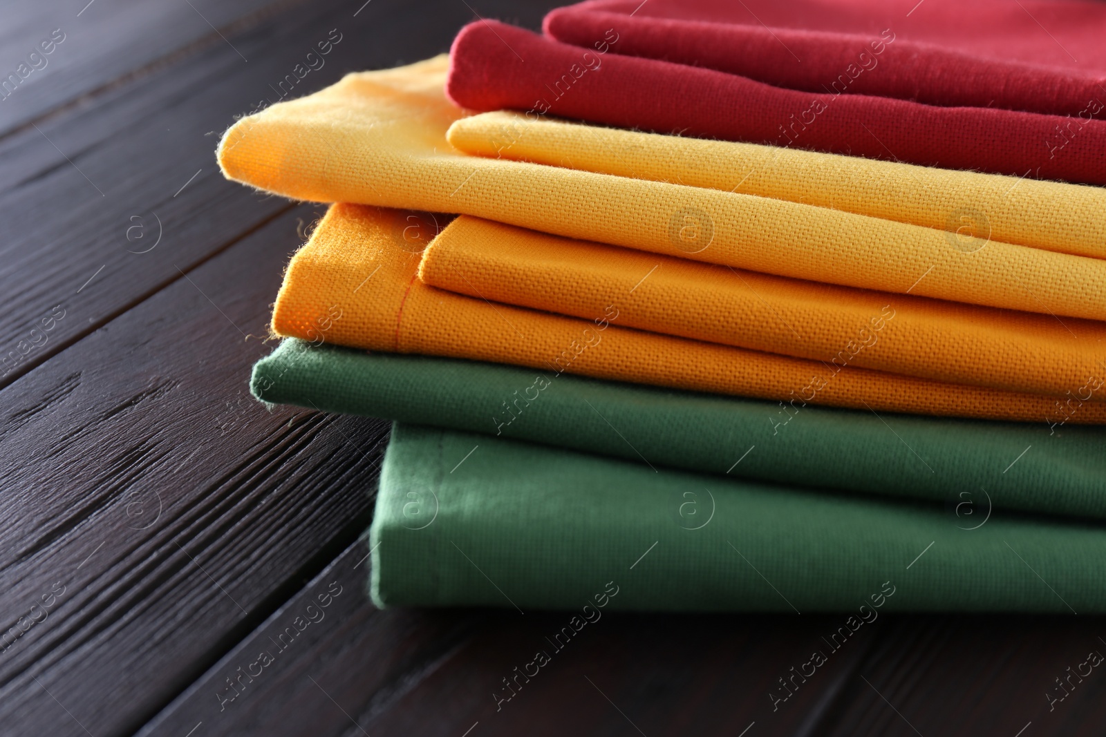 Photo of Different colorful napkins on wooden table, closeup