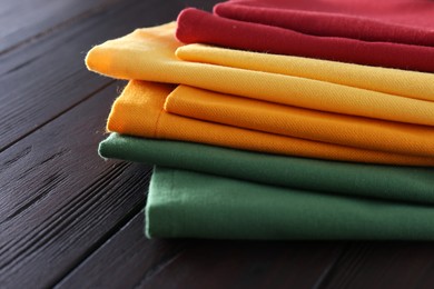 Photo of Different colorful napkins on wooden table, closeup