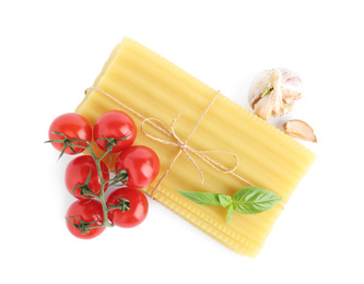 Photo of Uncooked lasagna sheets with cherry tomatoes, garlic and basil isolated on white, top view