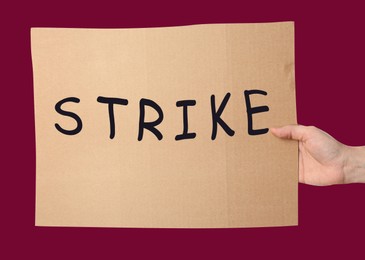 Woman holding Strike sign on color background, closeup